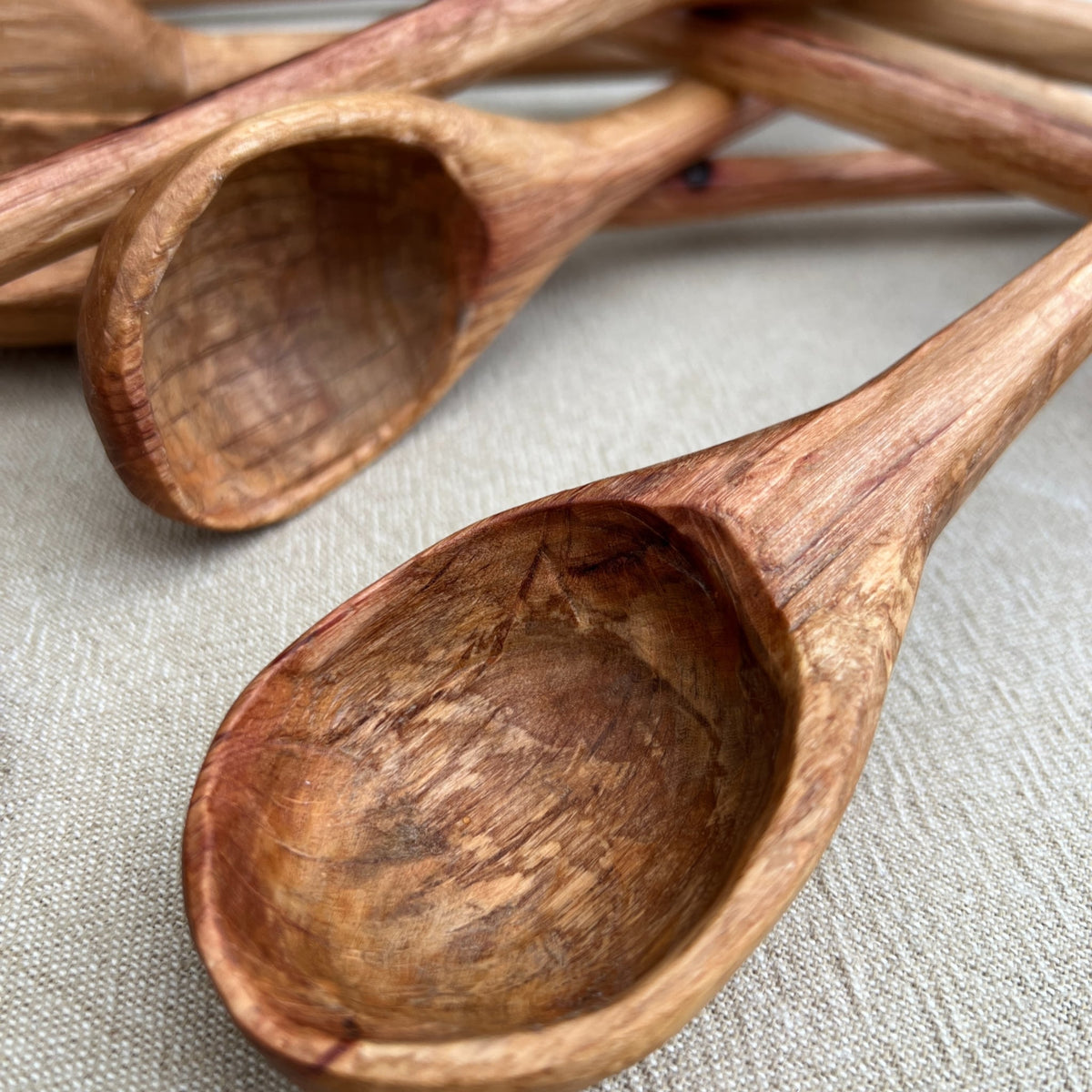 Close-up of the Straight Ladle by Luke Crouch, showcasing hand-carved details crafted from Australian She-Oak, with textured bowls and smooth handles, resting on a neutral-colored surface.