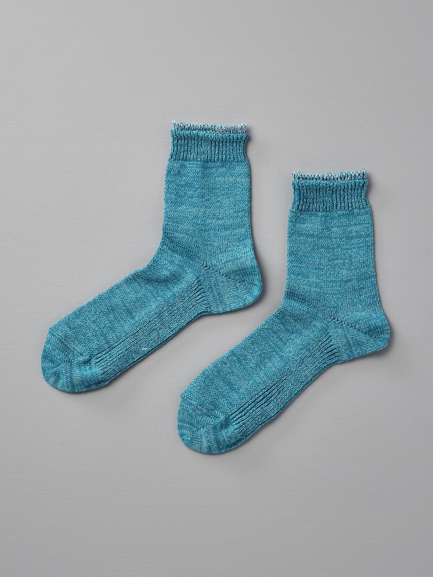 A pair of Mauna Kea Organic Top Switching Socks – Aqua, sized EUR 35—38, is laid flat on a light-gray surface.