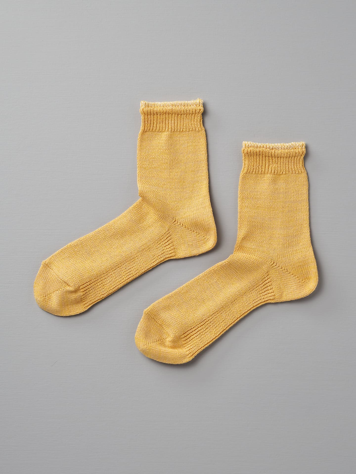 A pair of Mauna Kea Organic Top Switching Socks – Yellow, available in EUR 35—38 and EUR 39—42, is displayed on a grey background.