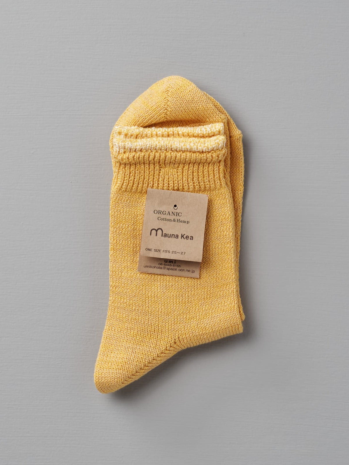 A pair of Organic Top Switching Socks – Yellow made of organic cotton and hemp, with a label reading &quot;Mauna Kea, One Size Fits All (cm 23—25).