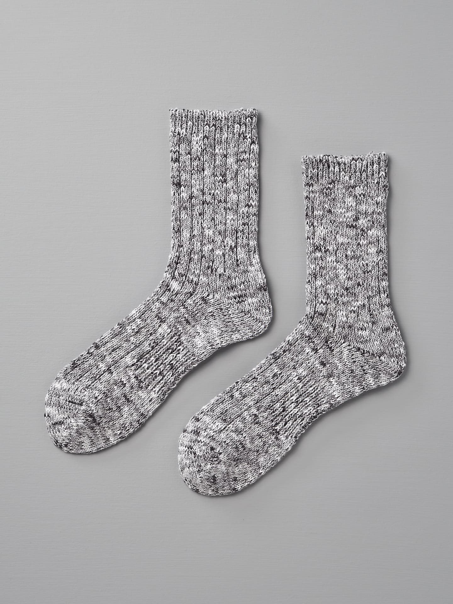 A pair of Mauna Kea Japanese Slub Rib Socks – Grey with a ribbed texture and slight marling, laid flat against a gray background, designed to fit sizes EUR 39-42.