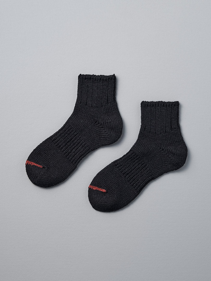 A pair of Mauna Kea Japanese Slub, Low-Cut Socks – Black on a grey background.