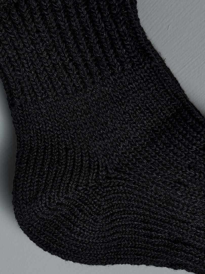 A close up of Mauna Kea Japanese Slub, Low-Cut Socks - Black on a grey surface.