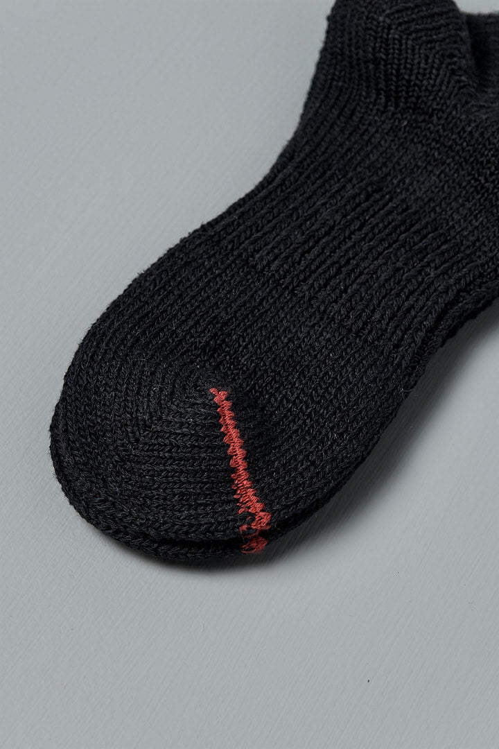 A close up of a Mauna Kea Japanese Slub, Low-Cut Socks in Black with red stitching.