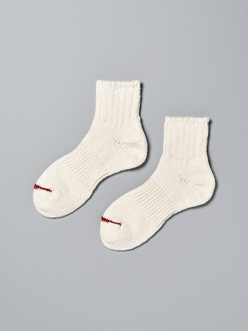 A pair of Mauna Kea Japanese Slub, Low-Cut Socks - Off White on a grey background.
