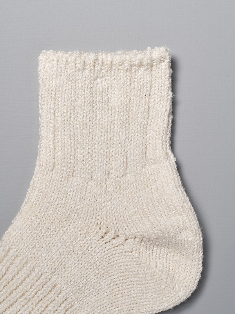 A close up of Mauna Kea Japanese Slub, Low-Cut Socks - Off White on a gray background.