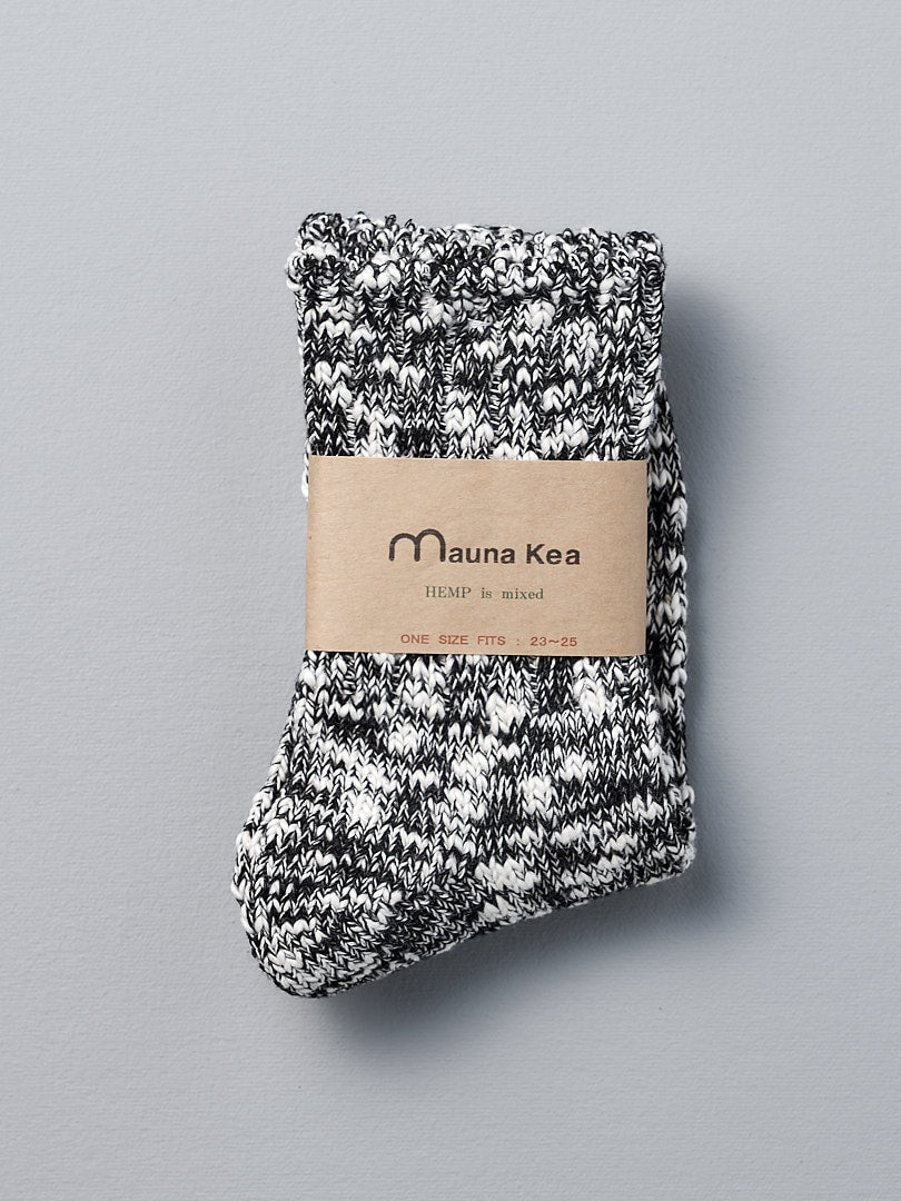 A pair of Japanese Slub Socks – Black crafted from a cotton and hemp blend, featuring a Mauna Kea label. These soft marled socks are meticulously crafted using vintage knitting machines.