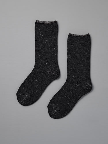 A pair of Nishiguchi Kutsushita Memeri Wool Silk Socks in charcoal, crew-length and made in Japan, laid flat on a plain grey background.