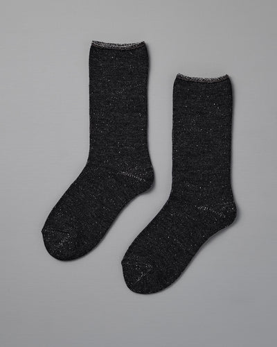 A pair of Nishiguchi Kutsushita Memeri Wool Silk Socks in charcoal, crew-length and made in Japan, laid flat on a plain grey background.