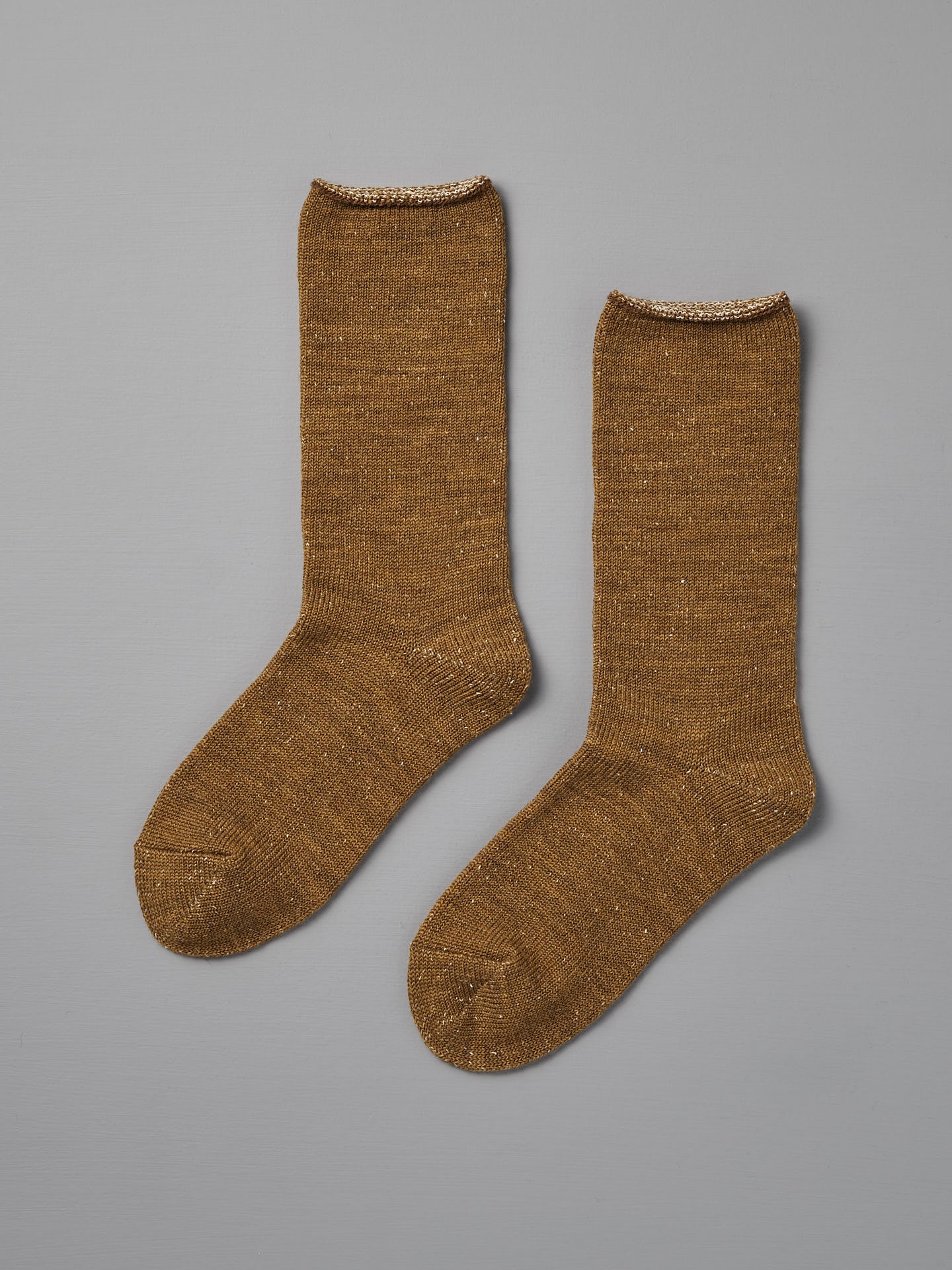 A pair of Memeri Wool Silk Socks in mustard by Nishiguchi Kutsushita, shown flat on a gray background. Made in Japan, these cozy socks blend warmth and style with a subtle sheen—perfect for any outfit.