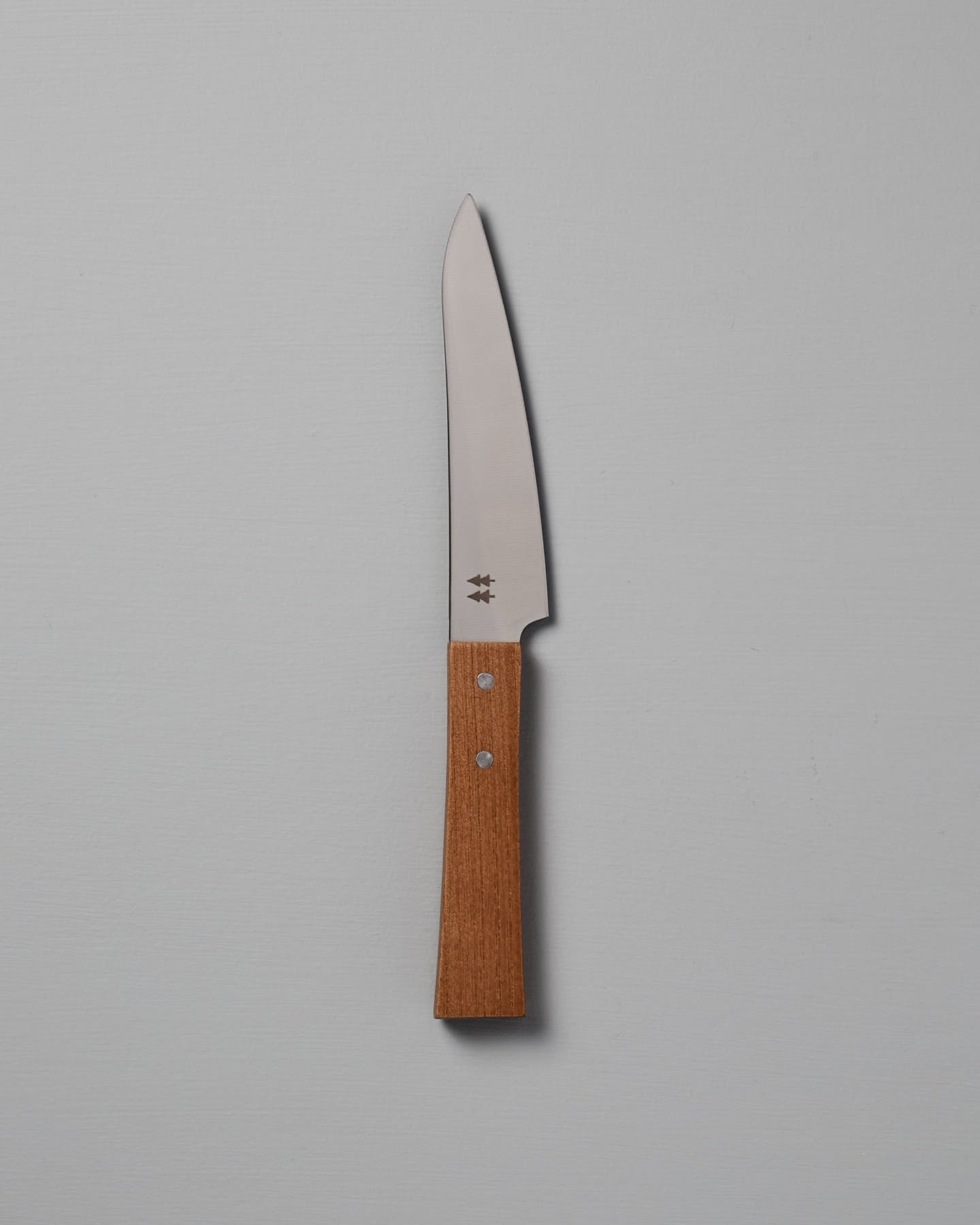 The Morinoki Petite Knife from Shizu Hamono Co. boasts an ergonomic grip and sleek stainless steel blade, complemented by a wooden handle, elegantly displayed against a light gray background.
