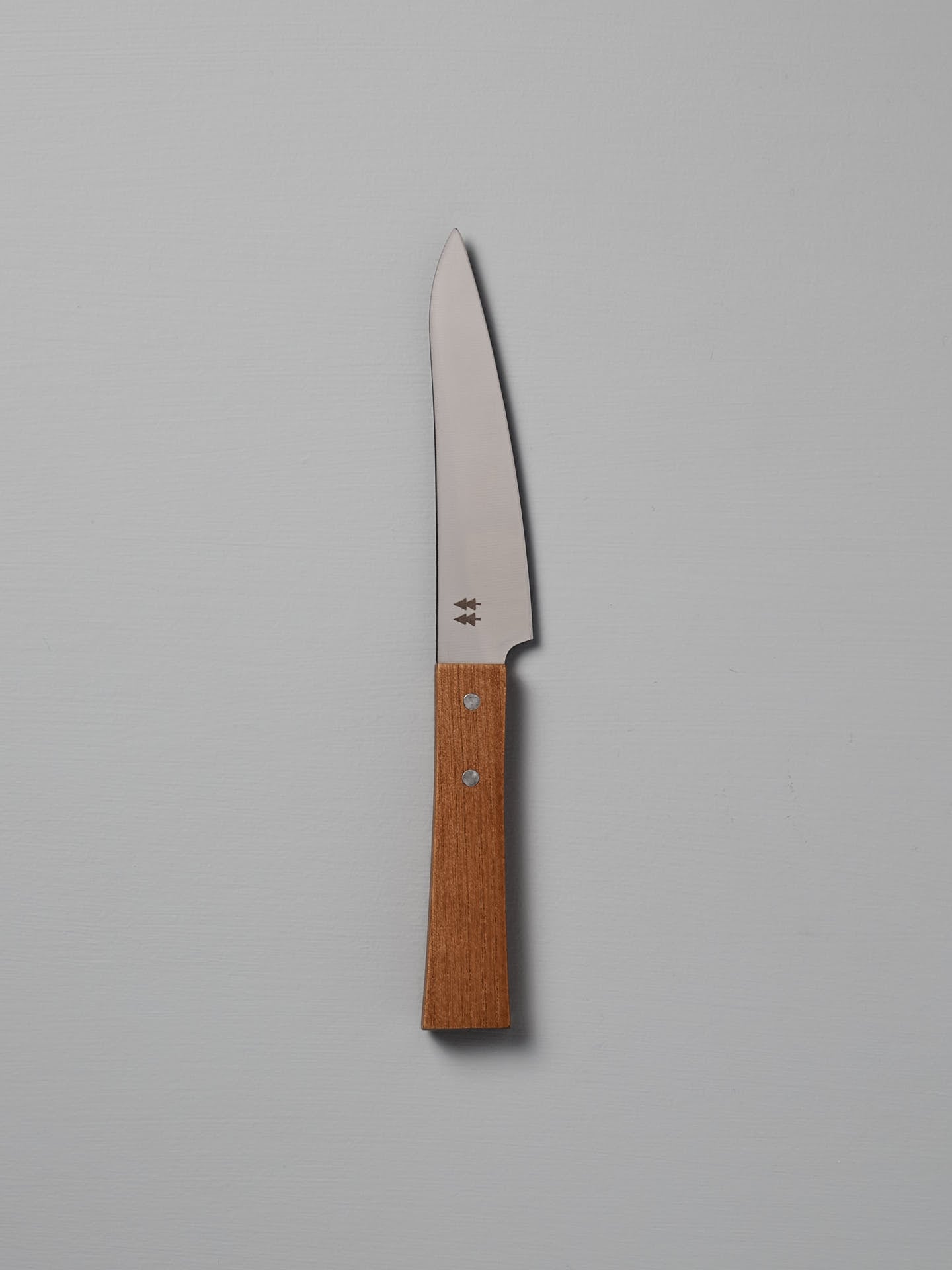 The Morinoki Petite Knife from Shizu Hamono Co. boasts an ergonomic grip and sleek stainless steel blade, complemented by a wooden handle, elegantly displayed against a light gray background.