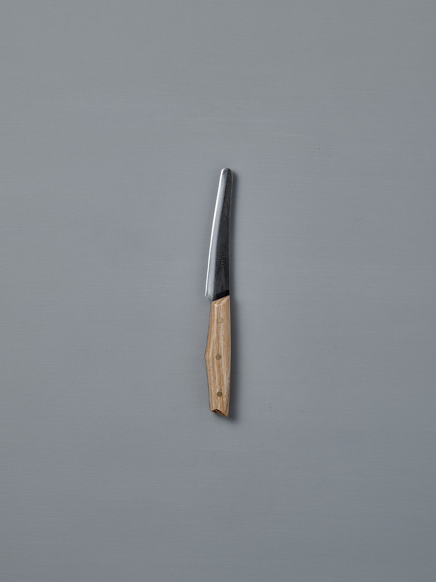 The №1 – Spread Knife, featuring a handcrafted wooden handle and a Swedish carbon steel blade, is displayed vertically against a plain gray background.