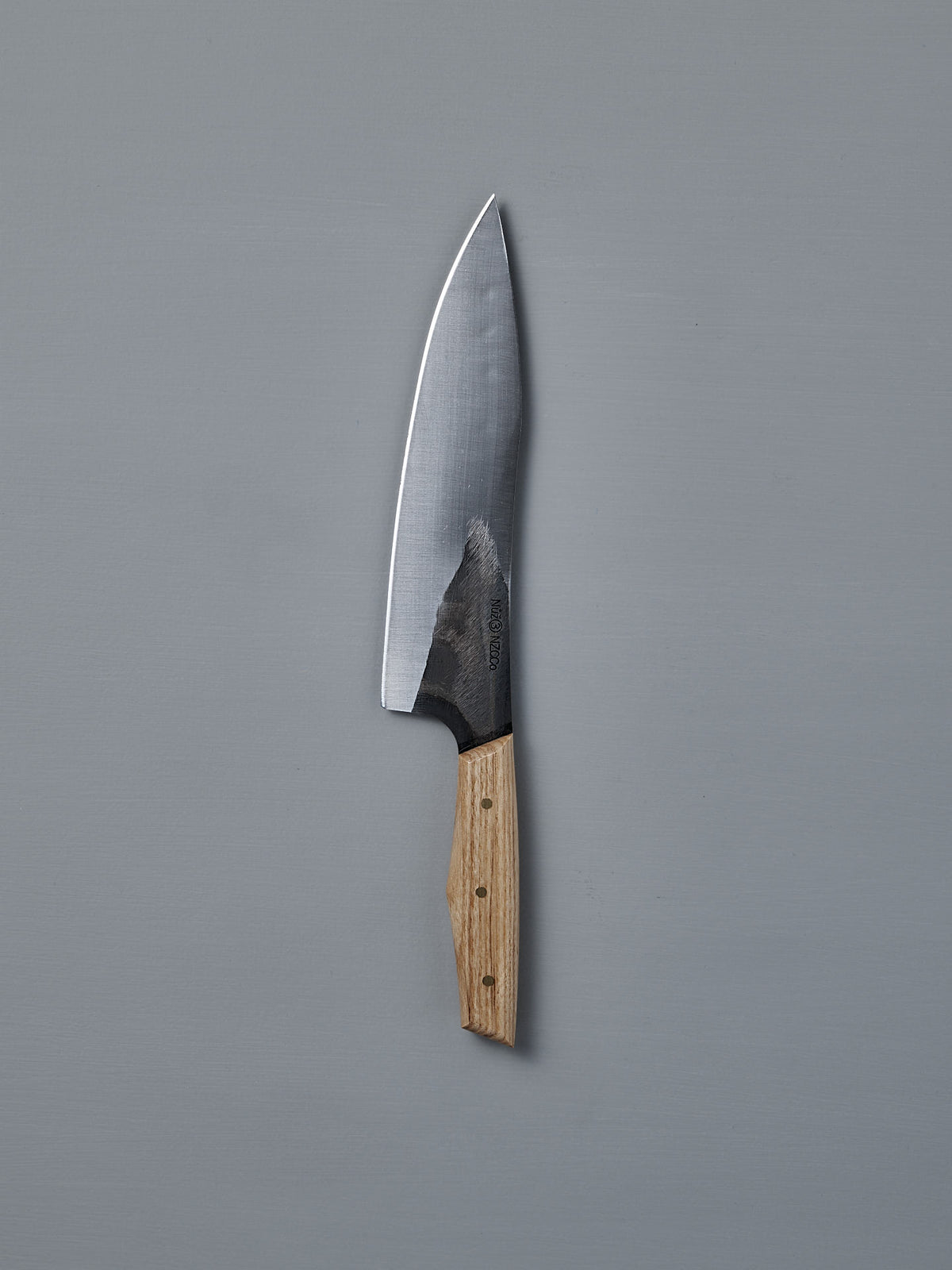 The №3 – Daily Knife, featuring a wide stainless steel blade and wooden handle, rests on a plain gray surface.
