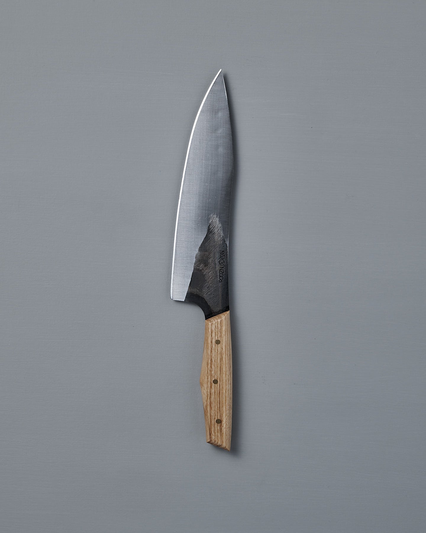 The №3 – Daily Knife, featuring a wide stainless steel blade and wooden handle, rests on a plain gray surface.