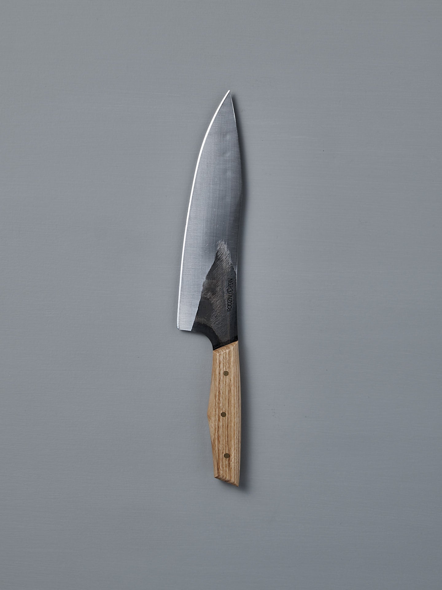 The №3 – Daily Knife, featuring a wide stainless steel blade and wooden handle, rests on a plain gray surface.