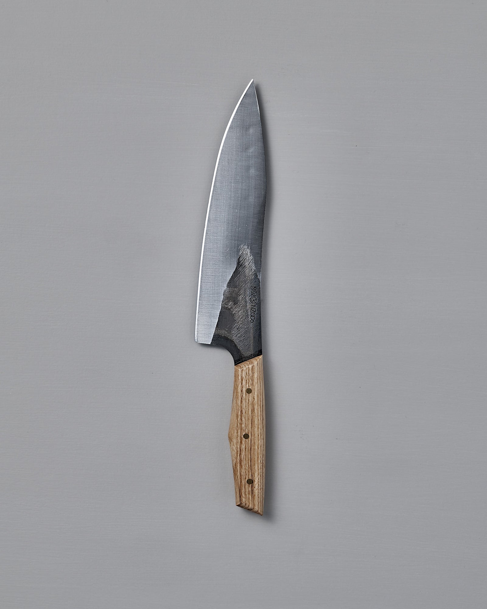The №3 – Daily Knife, featuring a wide stainless steel blade and wooden handle, rests on a plain gray surface.