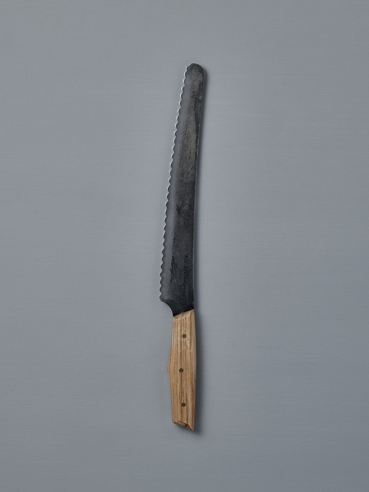 The №4 – Baker Knife, featuring a handcrafted serrated Swedish carbon steel blade and wooden handle, is displayed on a plain gray background.