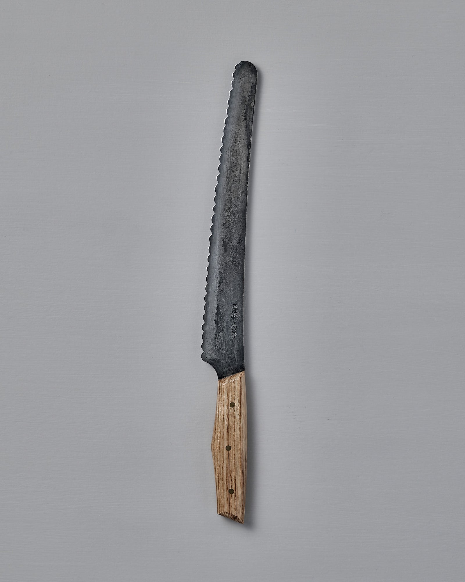 The №4 – Baker Knife, featuring a handcrafted serrated Swedish carbon steel blade and wooden handle, is displayed on a plain gray background.