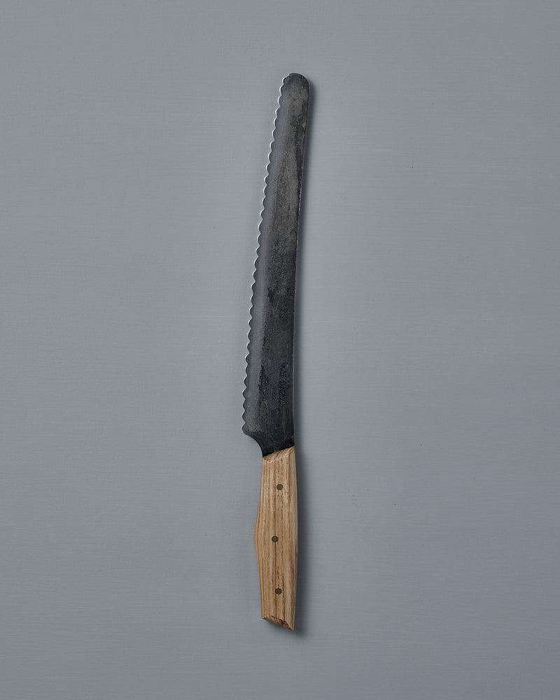 The №4 – Baker Knife, featuring a handcrafted serrated Swedish carbon steel blade and wooden handle, is displayed on a plain gray background.