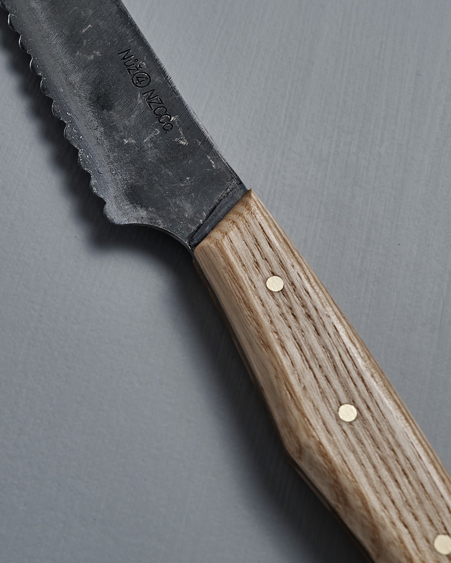 The №4 – Baker Knife, featuring a handcrafted serrated Swedish carbon steel blade and wooden handle, is displayed on a plain gray background.