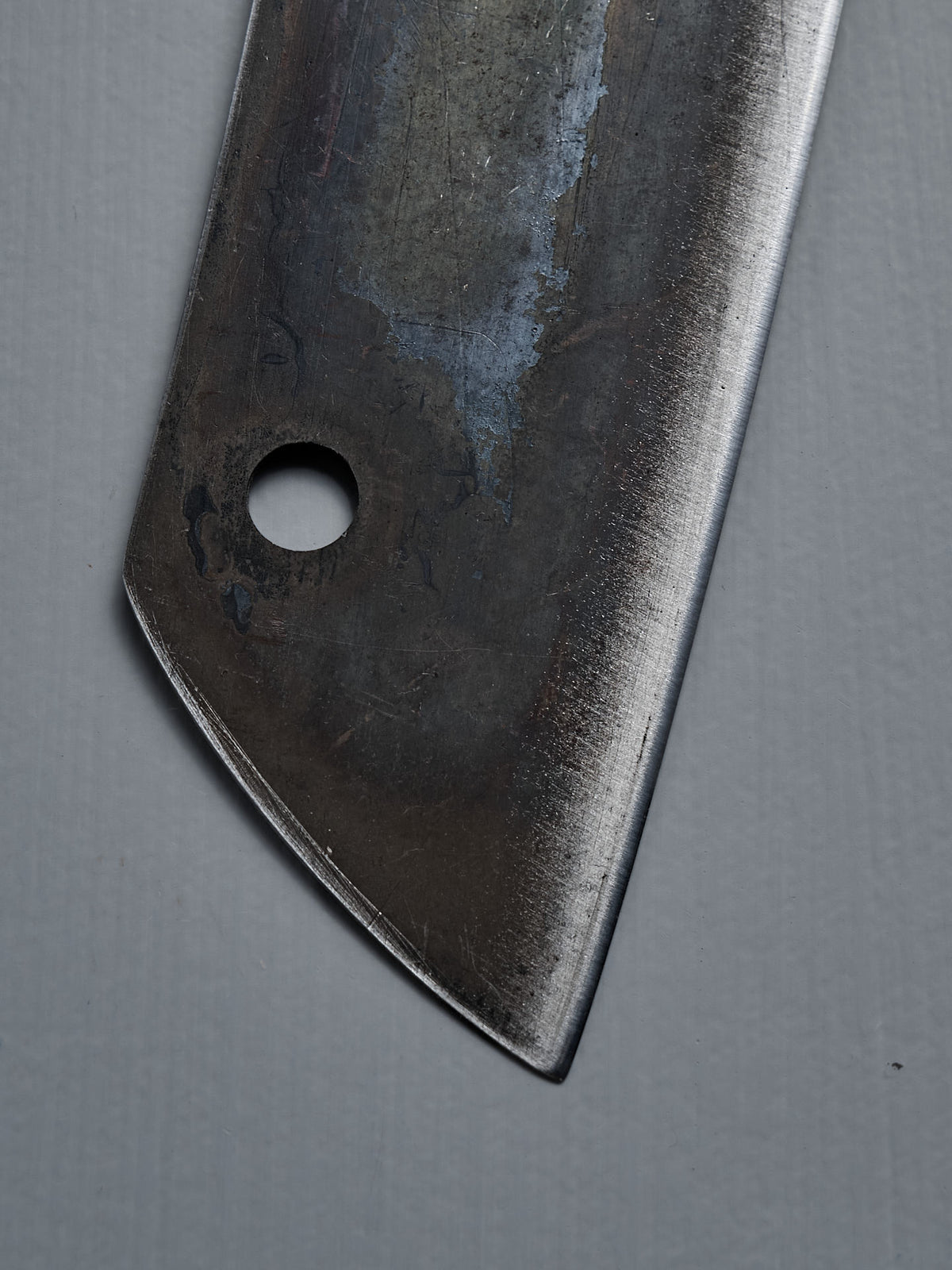 Close-up of the blade and hole of the №5 – Gourmet Knife, a handcrafted kitchen knife, set against a plain grey background.