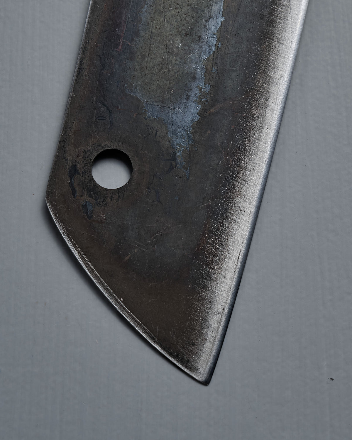 Close-up of the blade and hole of the №5 – Gourmet Knife, a handcrafted kitchen knife, set against a plain grey background.