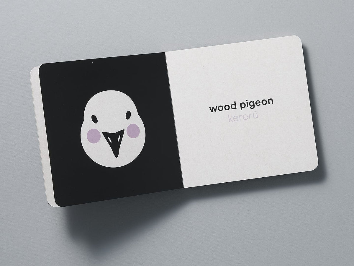 A business card with a minimalist New Zealand birds illustration, highlighting the wood pigeon (kereru), and the text &quot;wood pigeon kereru&quot; on a gray background from Native NZ Baby Meets Bird – by Kate Muir.