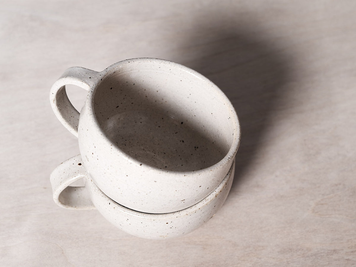 Handmade Nicola Shuttleworth white mugs stacked on top of each other, with a glossy glaze finish.