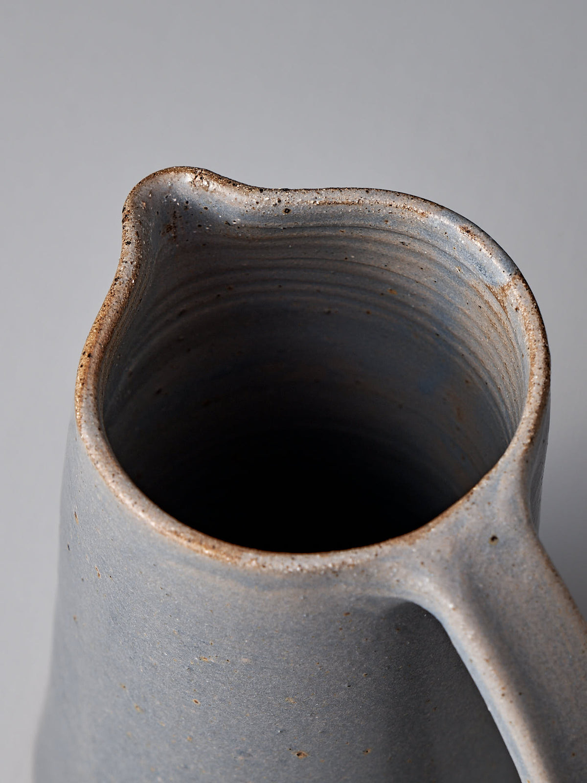 Top view of the Jug – Dusty Blue from Nicola Shuttleworth, featuring a weighted design with a handle and a textured, speckled gray-blue surface. The slightly irregular spout complements the satin glaze interior, which remains dark and unglazed to emphasize the artisanal quality of this handmade product.