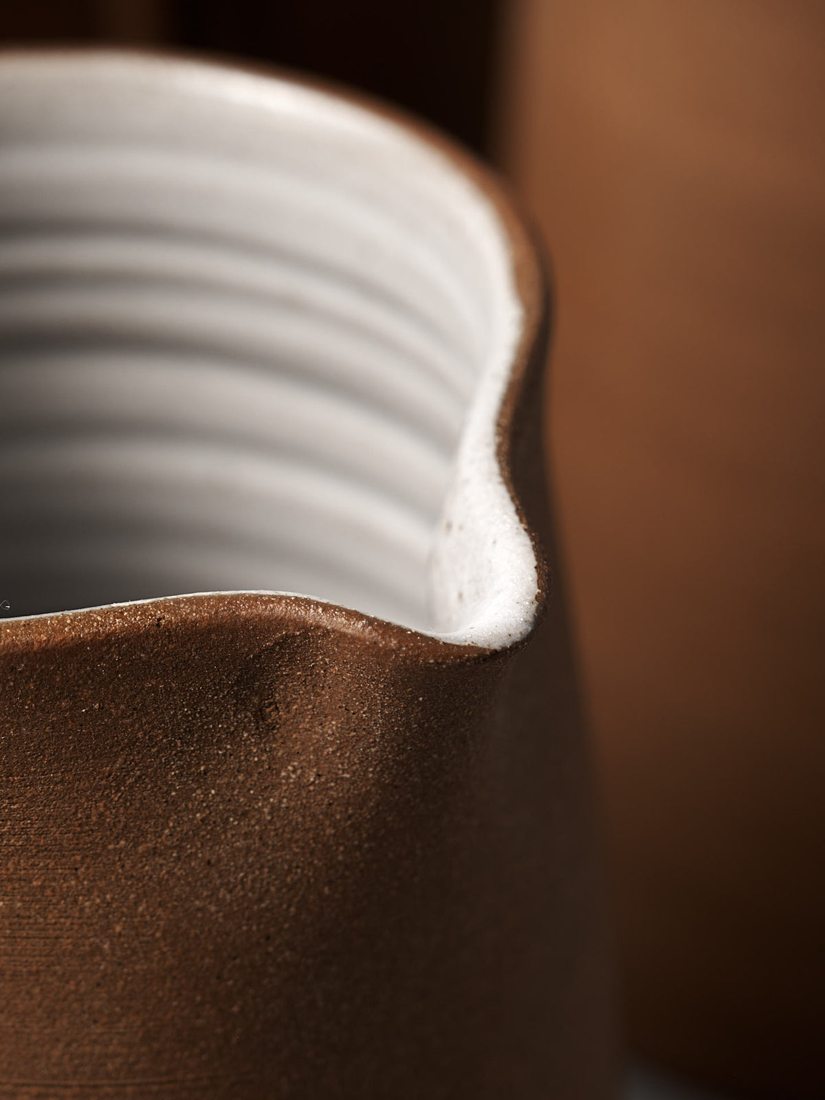 A close-up of the Jug – Textured by Nicola Shuttleworth, featuring a raw unglazed exterior, white ribbed interior, and an irregular wavy rim evocative of handmade ceramic design.