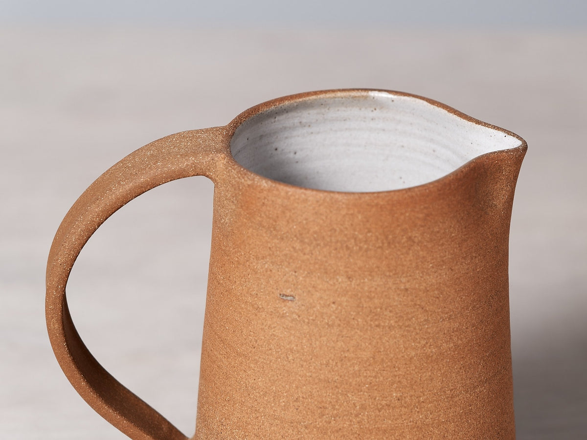 A Nicola Shuttleworth Textured jug sitting on a wooden table.