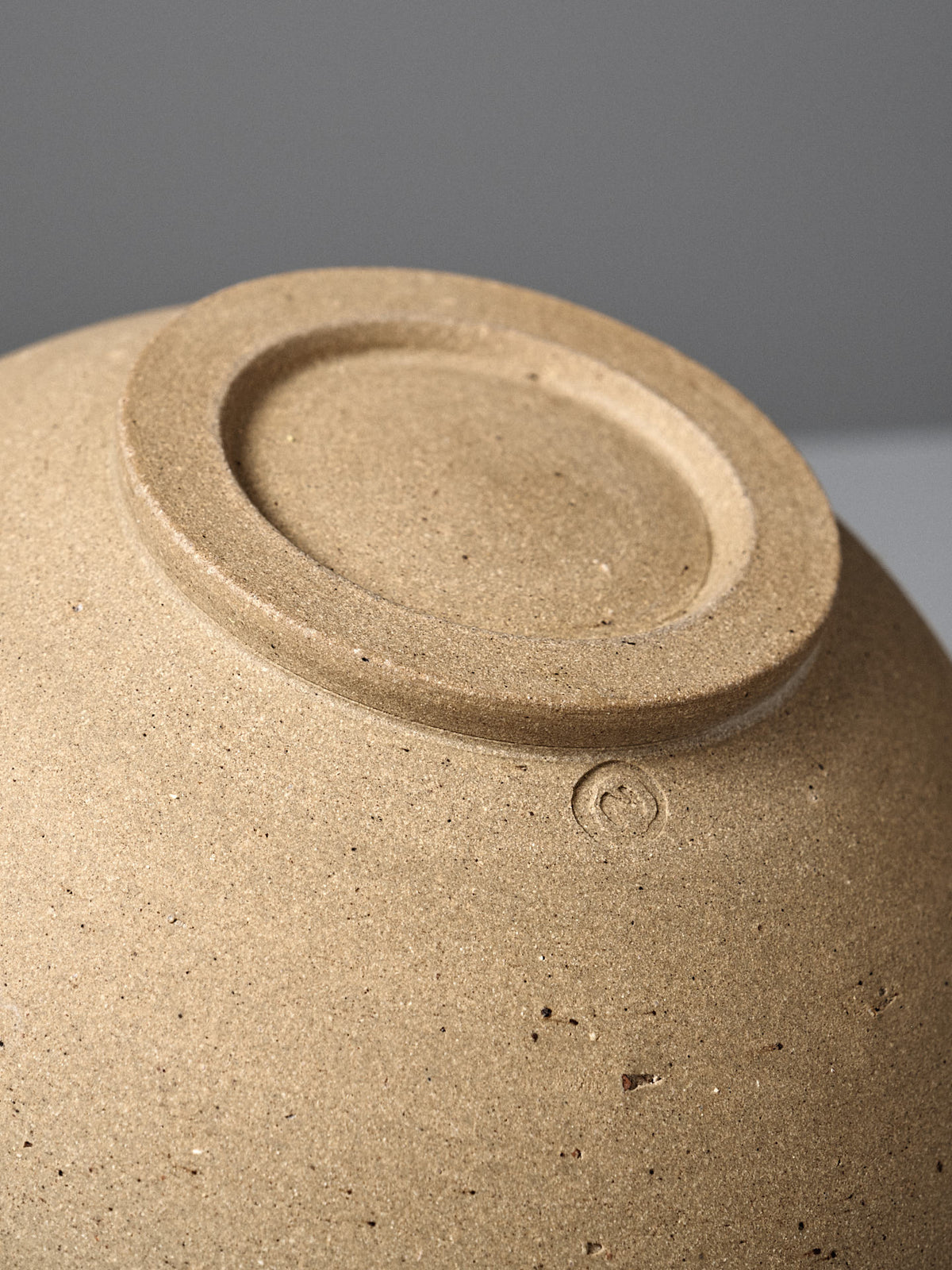 Close-up of the unglazed bottom of the Speckled Toast Serving Bowl – Medium, highlighting its handmade maker’s mark and textured ceramic surface.