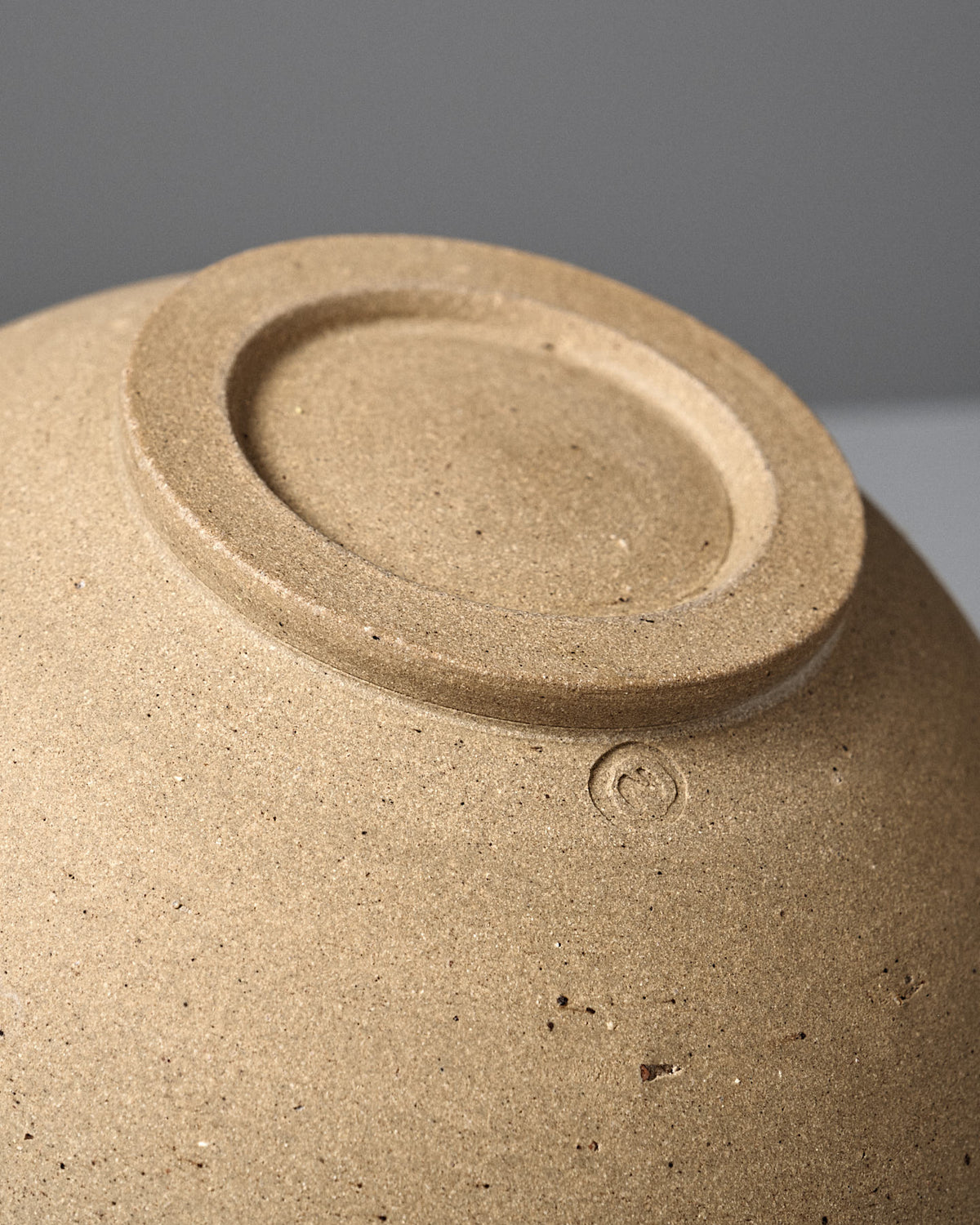 Close-up of the unglazed bottom of the Speckled Toast Serving Bowl – Medium, highlighting its handmade maker’s mark and textured ceramic surface.