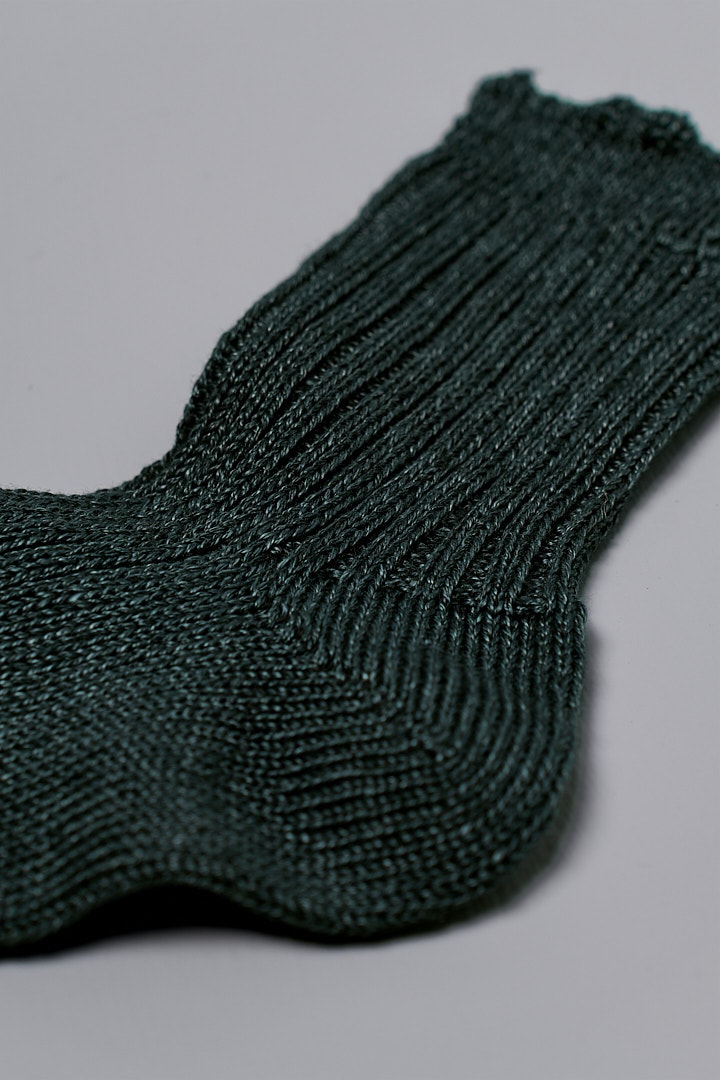 A pair of Praha Linen Ribbed Socks – Beach Plants by Nishiguchi Kutsushita on a grey surface.