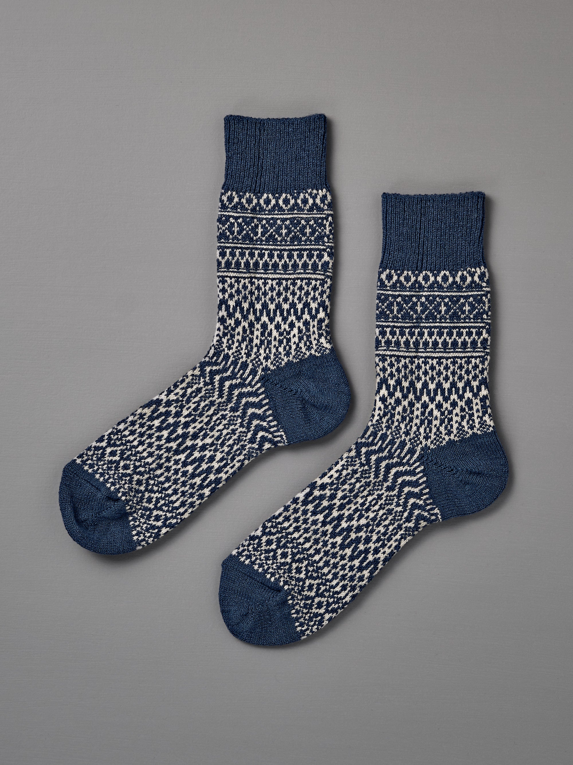 A pair of Oslo Wool Jacquard Socks in Seagull Blue, featuring a blue and white geometric knit pattern, is laid flat on a plain grey background. Includes women’s shoe size for easy selection.