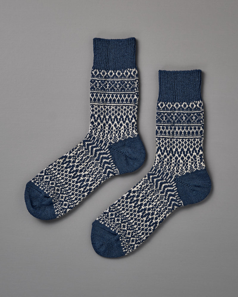 A pair of Oslo Wool Jacquard Socks in Seagull Blue, featuring a blue and white geometric knit pattern, is laid flat on a plain grey background. Includes women’s shoe size for easy selection.