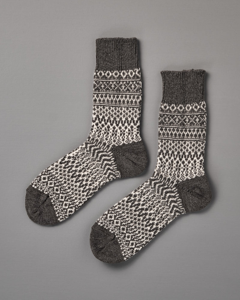 Oslo Wool Jacquard Socks – Grey: men's wool socks featuring black and white geometric patterns with dark gray heels, toes, and cuffs, displayed flat on a gray surface. Check our size chart for the perfect fit.