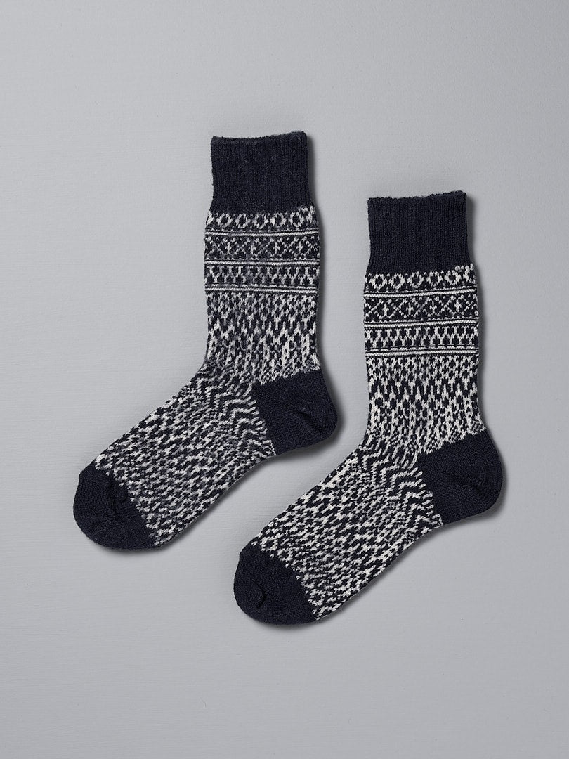A pair of Oslo Wool Jacquard Socks – Navy with incredible warmth on a grey background by Nishiguchi Kutsushita.