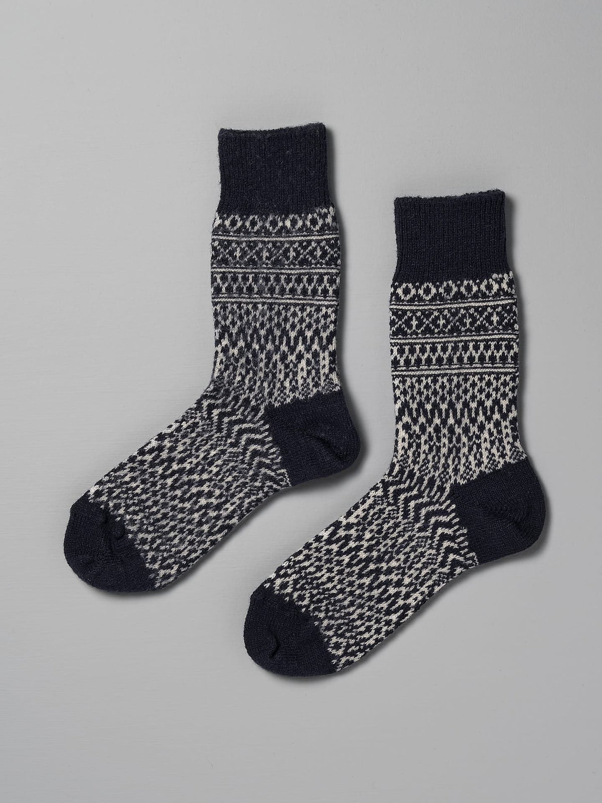 A pair of Oslo Wool Jacquard Socks – Navy by Nishiguchi Kutsushita, suitable for both women&#39;s and men&#39;s sizes, laid flat on a plain grey background.