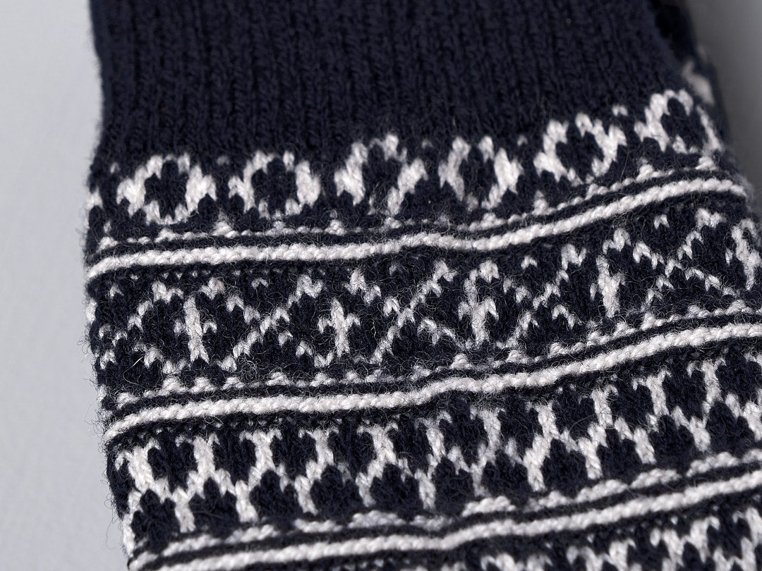 A close up of a Nishiguchi Kutsushita Oslo Wool Jacquard Sock in navy and white, offering incredible warmth with its pre-shrunk wool design.