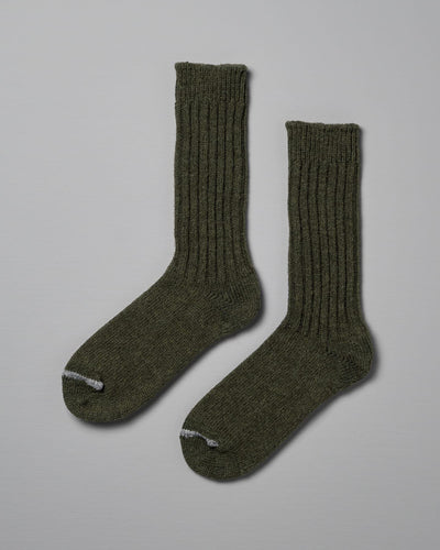 A pair of green knitted socks with ribbed cuffs and white toes, displayed side by side on a grey background, perfect for checking your Men's US size chart. Product Name: Praha Wool Ribbed Socks – Khaki Brand Name: Nishiguchi Kutsushita