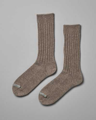 A pair of Praha Wool Ribbed Socks – Beige by Nishiguchi Kutsushita, displayed flat against a plain grey background. Both socks feature a small blue stripe near the toe area. Available in various sizes, including EUR and US (Men’s & Women's).
