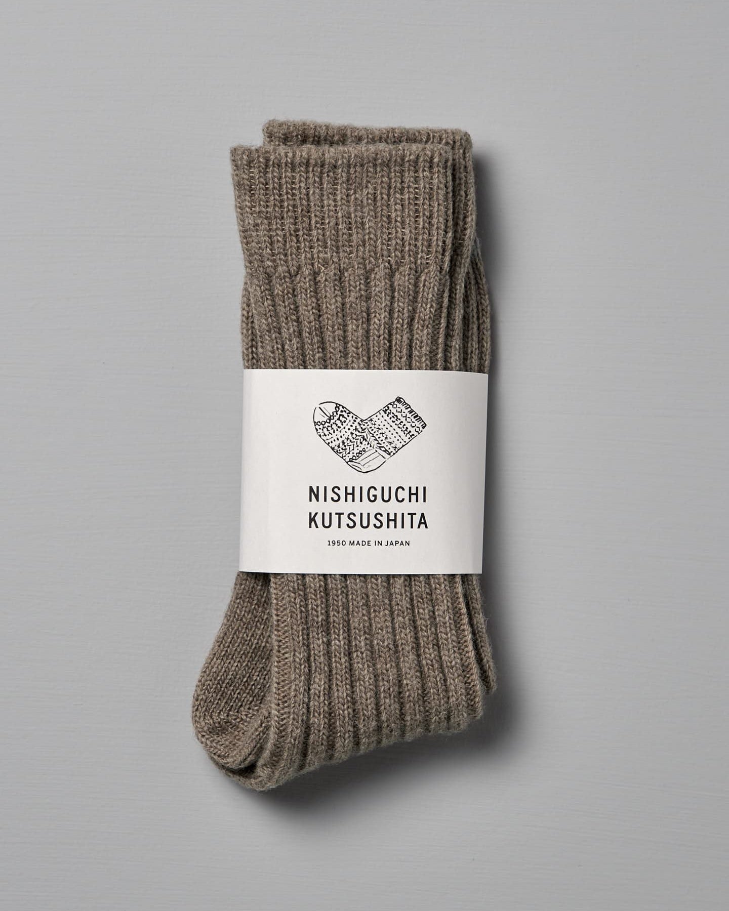A pair of Praha Wool Ribbed Socks – Beige by Nishiguchi Kutsushita, displayed flat against a plain grey background. Both socks feature a small blue stripe near the toe area. Available in various sizes, including EUR and US (Men’s & Women's).