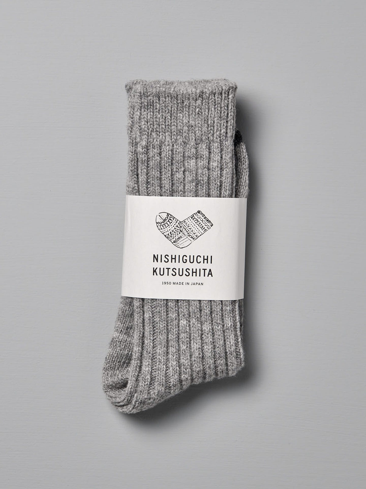 A pair of gray, ribbed Nishiguchi Kutsushita Praha Wool Ribbed Socks – Light Grey with a white label displaying the brand name, &quot;Made in Japan&quot; text, and US Men&#39;s sizes against a plain background.