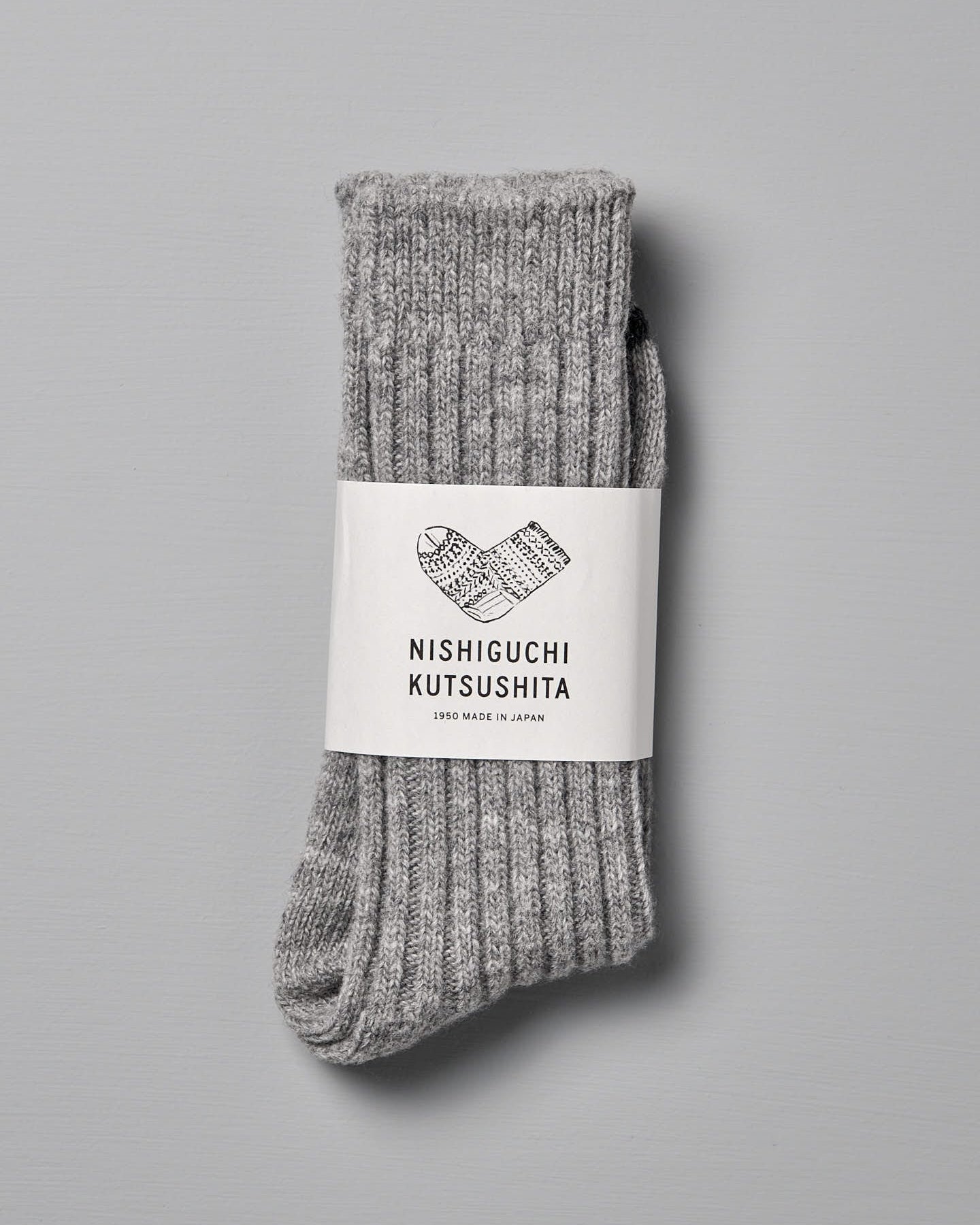 A pair of Praha Wool Ribbed Socks – Light Grey by Nishiguchi Kutsushita with ribbed texture and black toe tips, displayed against a light gray background, ideal for pairing with women's shoes.