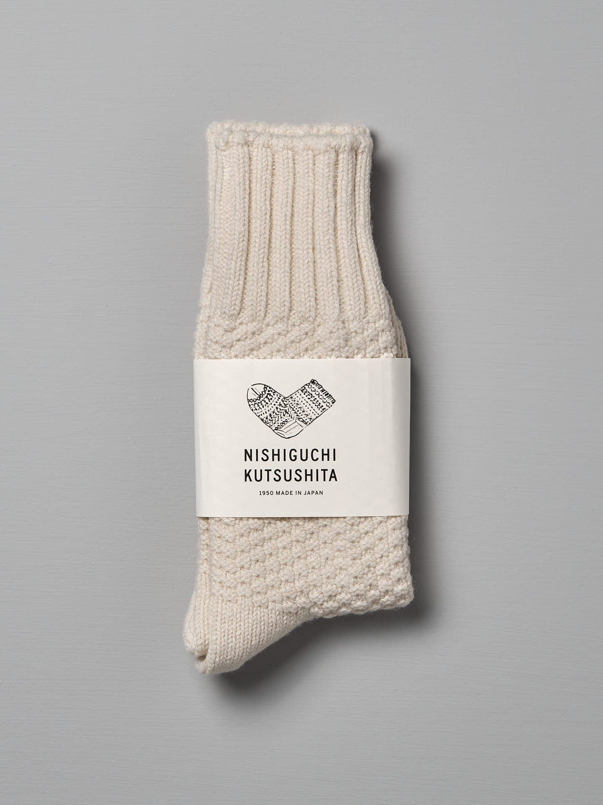 A single, folded pair of Wool Cotton Boot Socks – Ivory with a label that reads &quot;Nishiguchi Kutsushita,&quot; available in Men&#39;s US and Women&#39;s US sizes.