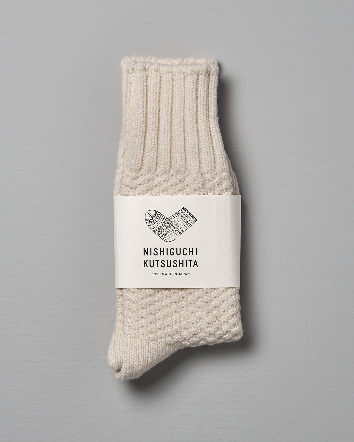 A single, folded pair of Wool Cotton Boot Socks – Ivory with a label that reads "Nishiguchi Kutsushita," available in Men's US and Women's US sizes.