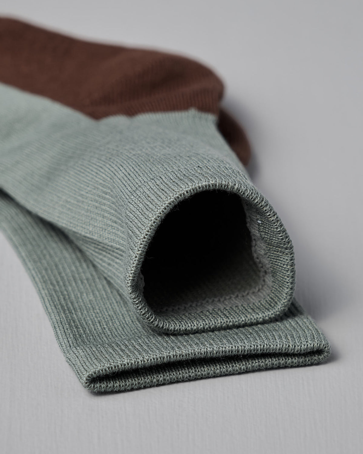 Close-up of folded Cotton Cashmere Walk Socks – Kusamochi by Nishiguchi Kutsushita, featuring light green and brown ribbed fabric on a light grey surface. Offered in multiple US women’s shoe sizes for the perfect fit.