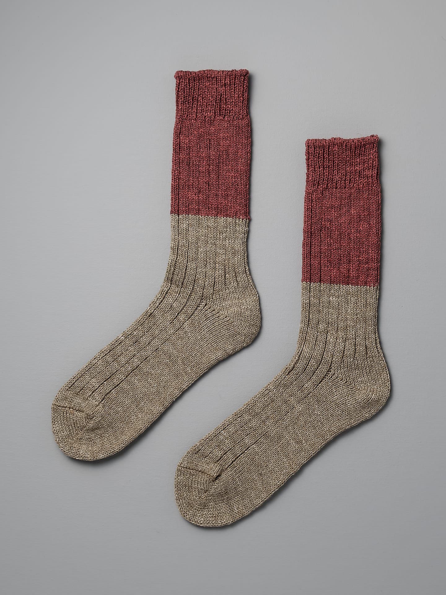A pair of Nishiguchi Kutsushita Boston Slab Socks – Red Brick with a red upper section and a gray lower section, placed side by side on a flat, gray background, are available in various US Women's Sizes.